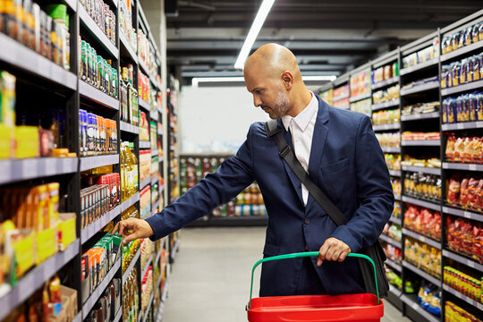 Grocery, shopping and shelves with man in supermarket for food search, savings and health sale. Budget, retail and promotion with person or customer at store for discount, product and consumer