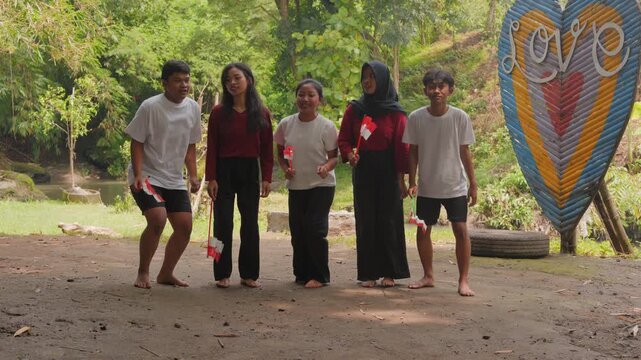 A group of Indonesian people are holding their country flag while jumping in excitement. Indonesia Independence Day concept.