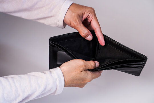 A person's hands holding open a completely empty black leather wallet, showing no cash or cards inside.