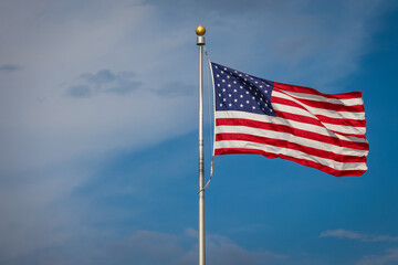 Obraz premium The United States of America flag waving in the wind on a sunny day