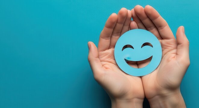 Hands holding a happy blue paper smiley face icon
