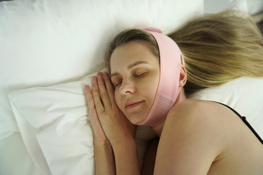 Young woman applying double chin reducer headband during self care before sleeping