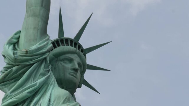 Statue of Liberty on Liberty Island, New York, United States. Blue cooper monument, symbol of democracy and patriotism near Manhattan, NYC USA. Clouds on sky. American independence. Torch and crown.