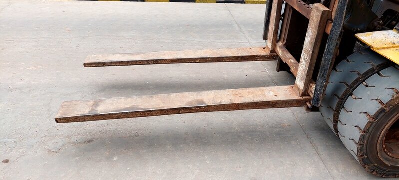 Mojokerto, East Java, Indonesia - February 2, 2023: Forklift forks, poorly maintained, rusty, concrete floor, bald forklift tires,