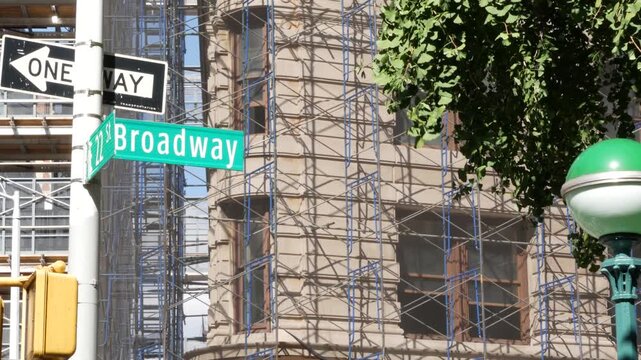 New York City Broadway street sign in Manhattan Midtown, United States. Urban road sign, traffic sign. Building architecture in Flatiron district. Crossroad with 5 fifth avenue. Subway metro entrance.