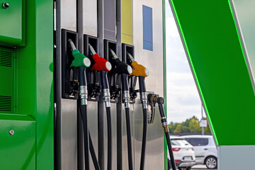 Fuel pump nozzles at modern gas station. Colorful fuel nozzles hang on a modern gas station pump with green, red, black, and yellow handles. © Iryna