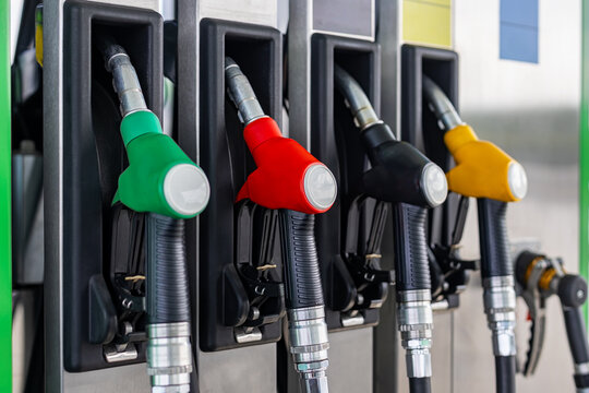 Colorful Fuel Pump Nozzles at Gas Station. Close-up of colorful fuel pump nozzles in green, red, black and yellow resting in holders at a modern gas station.