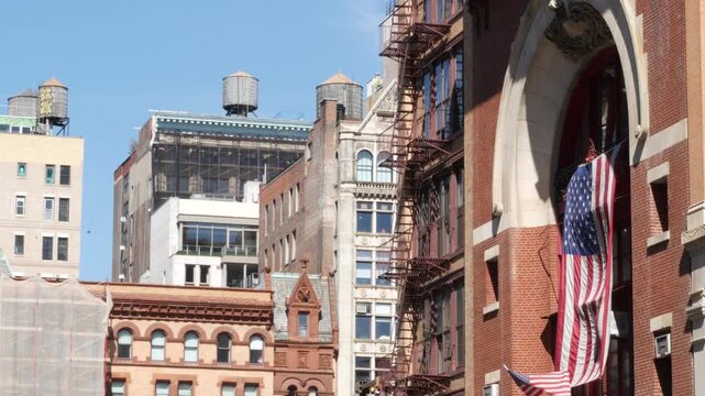 New York City classic Manhattan historic building architecture 1899, United States. Red brick house, USA american flag. Firehouse or fire station on Great Jones Street. Water tower tank, fire ladder.