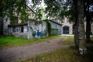 Old industrial brick building with street art deer mural in courtyard © Janica