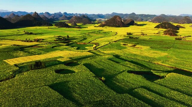 Agricultural crop patterns stretch across a wide valley floor beneath rugged hills.