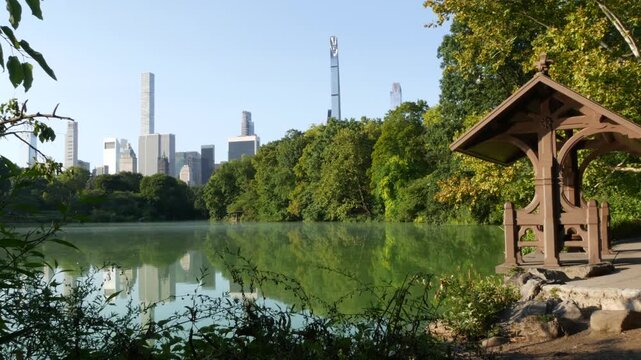 New York City skyline cityscape from Central Park, United States. Midtown skyscraper towers, building architecture and lake in summer. Pond water and greenery in NYC park, USA. Hernshead, alcove view.