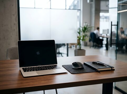 Modern corporate office workspace setup with open laptop, notebook, pen, and mouse on wooden desk in bright conference room background