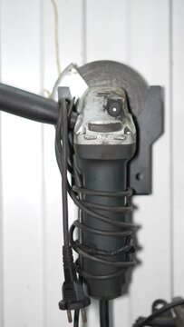 Angle Grinder Mounted on Wall Bracket, Cord Coiled Around Handle, Industrial Workshop Setting
