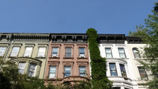 New York City townhouse buildings, brownstone row houses in Manhattan or Brooklyn, United States of America. Classic buildings on residential district street. Real estate property. Rowhouse townhome.