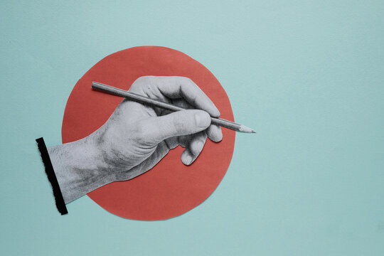Hand holding pencil and writing on blue paper cutout background