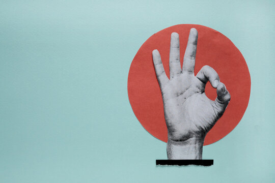 Hand showing ok sign gesture on blue paper cutout background