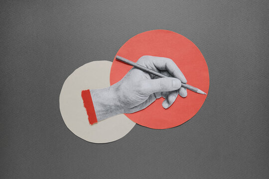 Paper cutout hand writing with pencil on geometric circles background