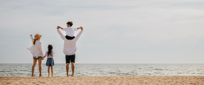 A heartwarming family moment at the sunset sea beach with raised arms and relaxation. The father carrying his son on shoulders epitomizes the carefree joy of a delightful beach vacation.