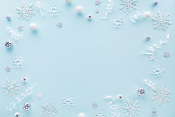 Obraz premium Festive Christmas and New Year holiday frame border from white snowflakes, silver baubles ornaments and winter decoration top view.