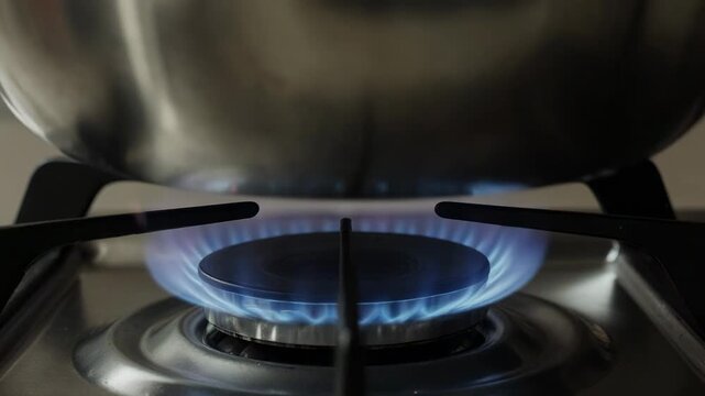 Gas stove burner igniting with blue and orange flames during cooking preparation