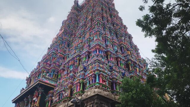 4K video panning upward from the base to the top of the ornate gopuram of Meenakshi Amman Temple in Madurai, Tamil Nadu, India, revealing intricate sculptures and colorful Dravidian architecture.