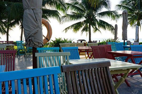 Vibrant Outdoor Seating Area Surrounded by Lush Palm Trees and Tranquil Ocean Views, Perfect for Relaxation and Leisure Among Colorful Furniture