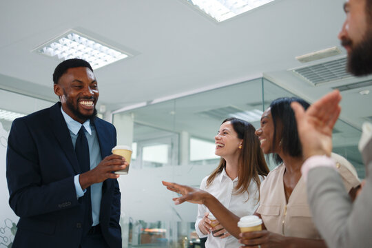 Diverse business professionals sharing a cheerful moment and laughing together during a casual office break, holding coffee cups and enjoying a positive team interaction