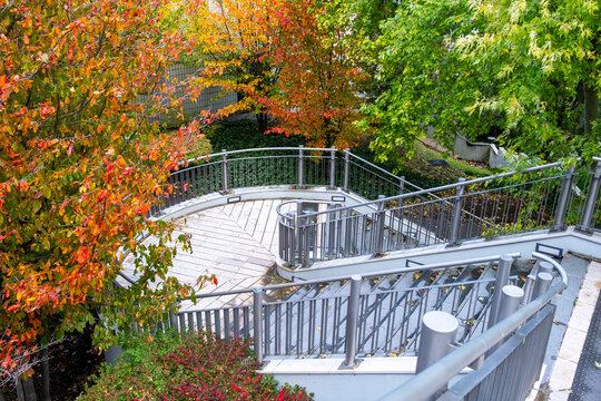 Curved outdoor stairs and railings wind through colorful autumn trees in La Defense in Paris France connecting public space with landscaped urban design