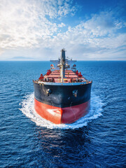 Close-up front view of a universal bulk carrier cargo ship traveling over blue ocean © moofushi