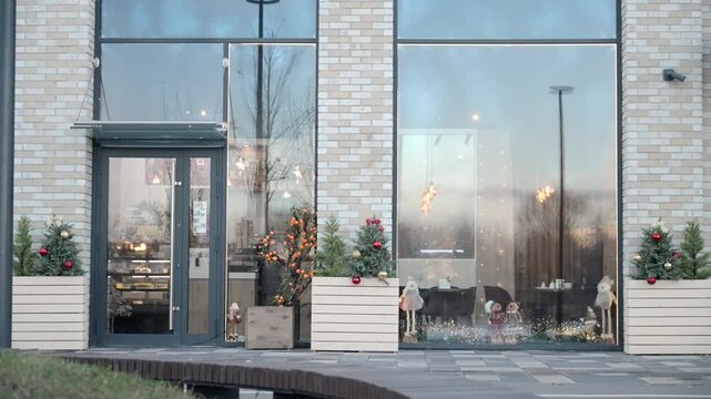 Modern brick storefront with frosted glass windows, dark metal entrance, and festive holiday greenery in calm urban setting