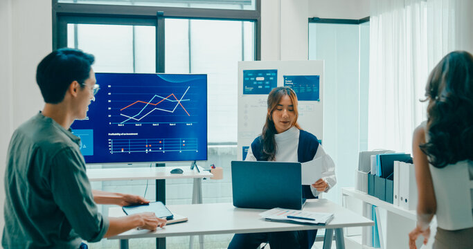 Group of Asian businesspeople work together discuss plan idea with investment data profit sale statistics in business meeting in office. Financial generation z team brainstorm on e-Commerce project.