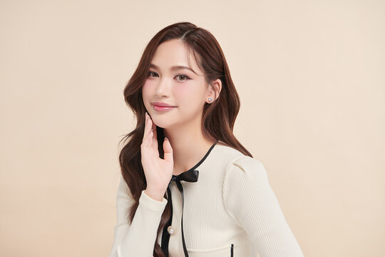 A beautiful young Asian woman with clean, fresh skin against a beige background. Skincare, facial treatment, cosmetology, beauty, and spa. An elegant portrait of an Asian woman.