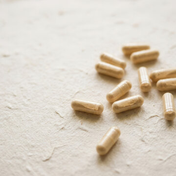 Healthcare Capsules Scattered On A Textured Surface For Wellness Concepts