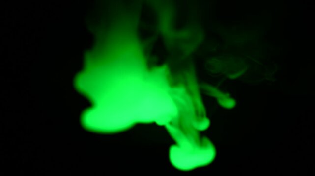 Slowly spreading green smoke against a black background, the concept of penetrating toxicity.