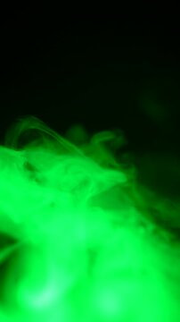 Green smoke, slowly swirling against a black background, gradually fills the entire space with a haze.