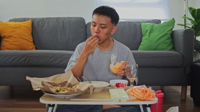 Young man eating karedok or traditional indonesian salad with crackers and rice at home