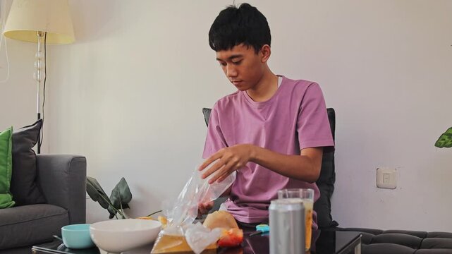 Young man Preparing meal by cutting open plastic bags before eating batagor