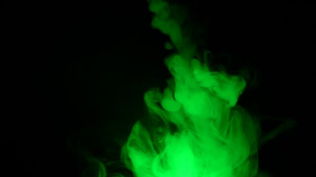 Green smoke, slowly swirling against a black background, gradually fills the entire space with a haze.