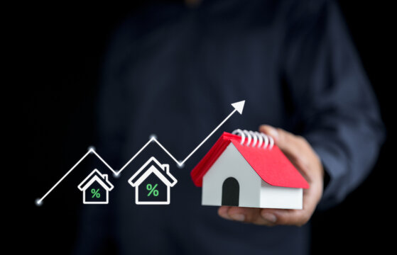 Mortgage interest rate concept with a wooden house model and magnifying glass, representing home loans, real estate financing, property investment, refinancing, and housing market analysis.