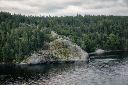 Ein massiver Felsvorsprung in den Stockholmer Sch&auml;ren, der durch einen Wald ins Meer verl&auml;uft