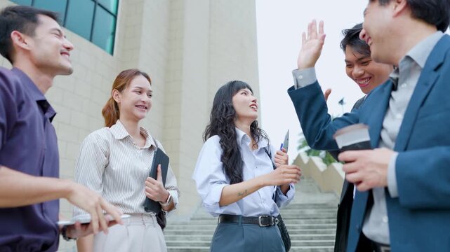 Diverse business team outdoors smiling and stacking hands in a unity gesture, symbolizing teamwork, collaboration, and commitment during a casual corporate meeting.