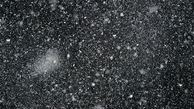 Fine white powder particles swirling in cinematic motion against a dark background