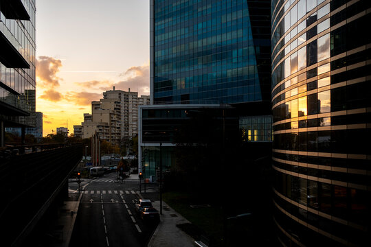 Street between modern office buildings at sunset in La Defense Paris France showing a dramatic urban corridor within the business district