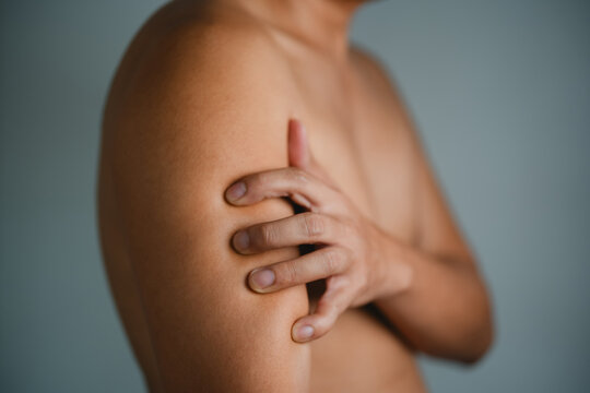 man itching and scratching on arm from itchy dry skin eczema dermatitis 
