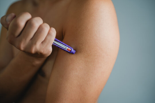 Blue self injection pen near man shoulder. Medicine and treatment concept 
