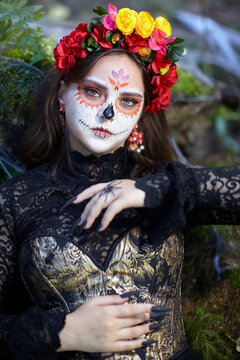 Halloween beauty portrait of young woman in nature. Female face adorned with Santa Muerte makeup.