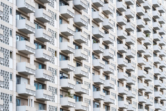 Repeating balconies create a rhythmic geometric facade pattern with strong perspective across dense building architecture in a tightly framed view