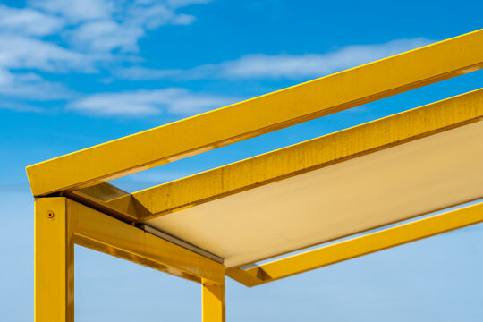 Bright yellow canopy against blue sky creates minimal geometric lines and bold color with generous copyspace in a clean background