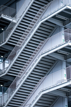 Repeating metal staircases create an abstract architectural pattern with strong lines and industrial geometry in a tightly framed detail