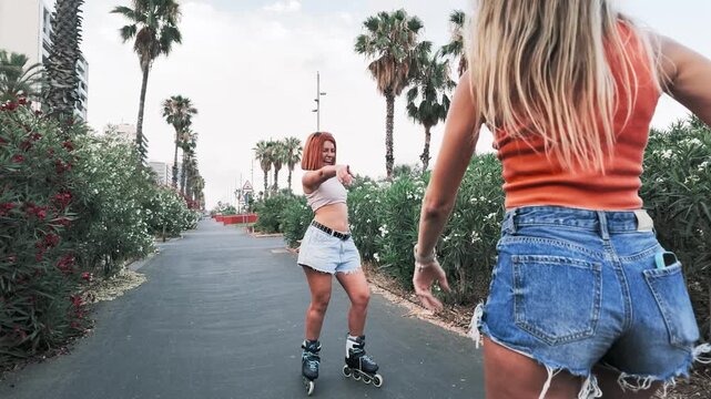 Happy friends dancing and rollerblading backwards in a park